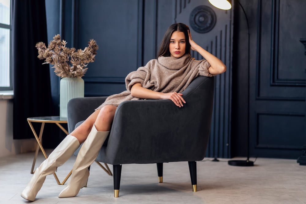 femeie imbracata in rochie tip pulover cu cizme crem inalte